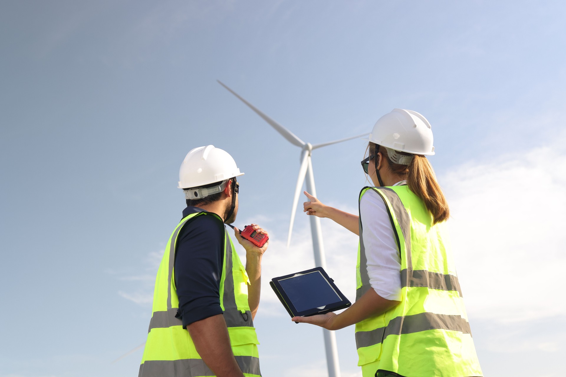 Electrical  engineers working on installation plans by drawing blueprints with coworkers in wind farms